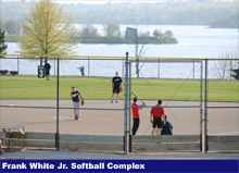 Softball players on a field playing with the water in the background