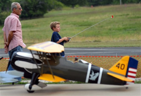A man and boy playing with remote controlled airplanes