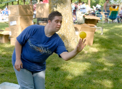 A girl in a blue shirt throwing a yellow ball